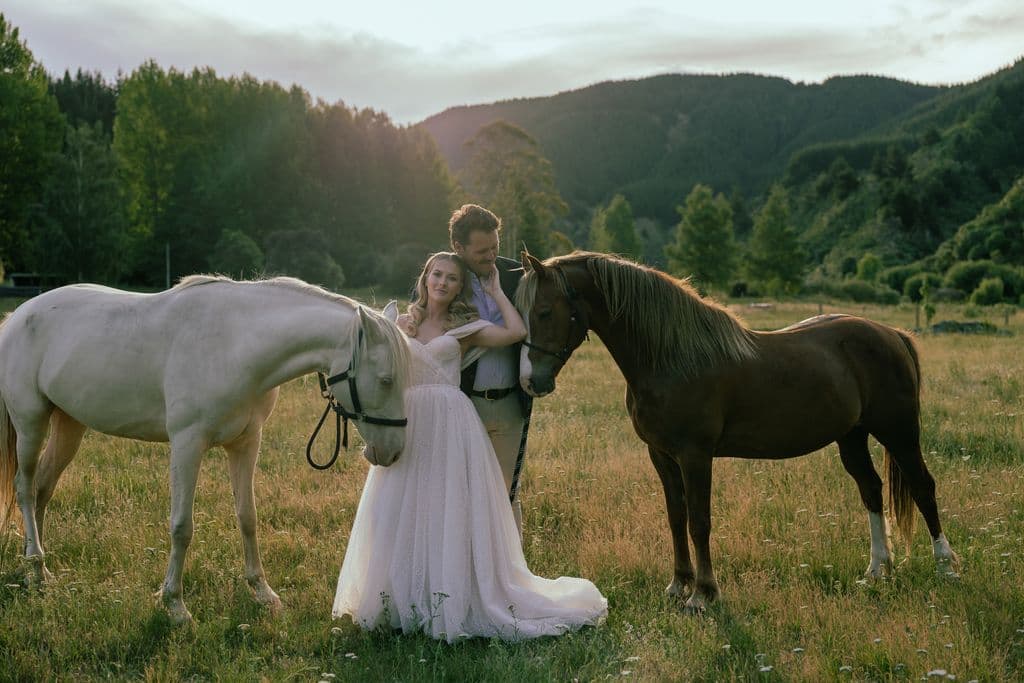 Destination wedding venue in Hawke's Bay. Rustic farmstay idyllic riverfront location - married couple with beautiful horses at sunset
