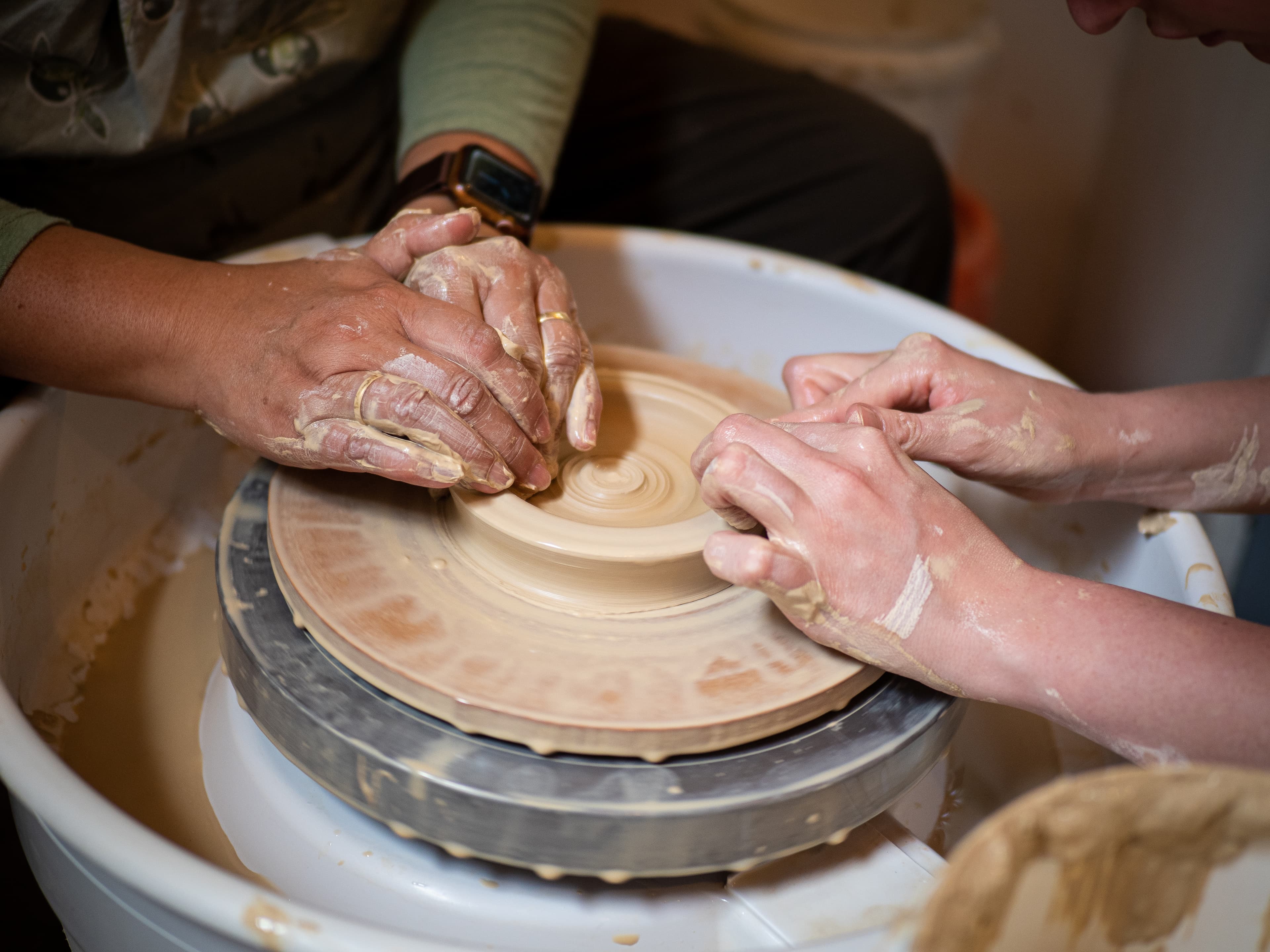 Pottery classes, photo with 2 hands on a pottery machine